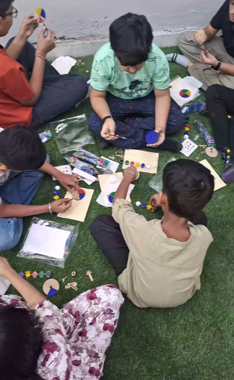 Children painting colour-wheel spinners on a mat at a football-themed birthday party in Delhi — Kraftykinni