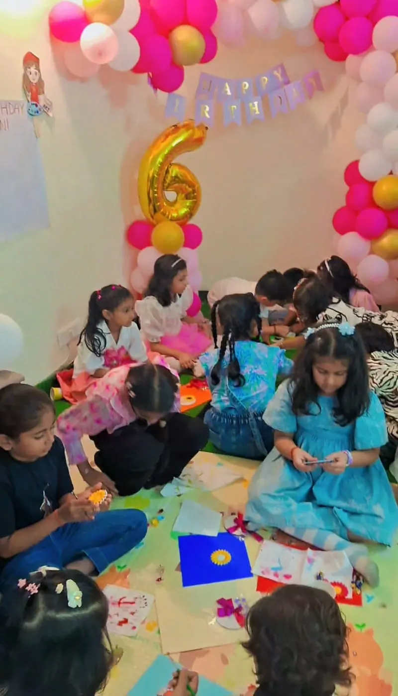Children painting fridge magnets on coloured sheets at a pink-and-gold birthday party at home in Noida — Kraftykinni